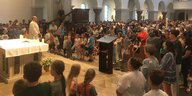 Blick aus dem Altarraum in die überfüllte Kirche, links im Bild steht Pfarrer Eggers, der auf seine Gemeinde guckt.