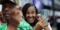 Eine junge Frau schaut ins Smartphone und lacht
