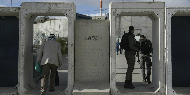 Ein Mann überquert einen Militärkontrollpunkt aus Beton neben Sodlats