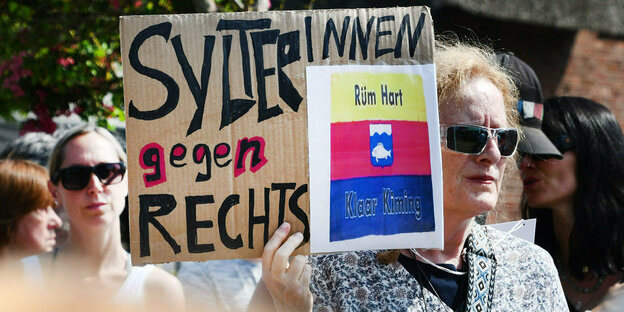 Eine Frau mit Sonnebrille hält ein Plakat "Sylterinnen gegen Rechts"