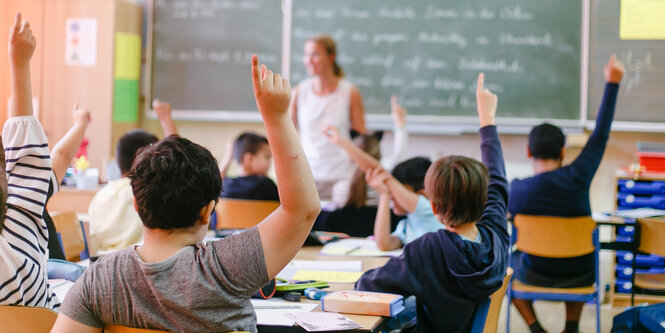 Kinder in einer Schulklasse melden sich