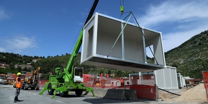 Ein Bagger hebt ein Fertigbauelement für ein Gebäude in die Höhe