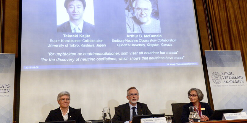 Mitglieder der Nobelversammlung vor Fotos der Preisträger