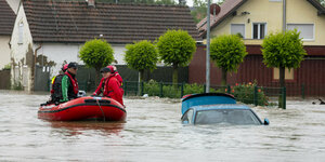 In Babenhausen fährt die Wasserwacht mit einem Schlauchboot durch überflutete Straßen.
