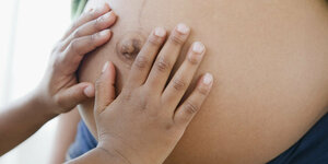 Ein Kind fast an den Bauch einer Hochschwangeren.