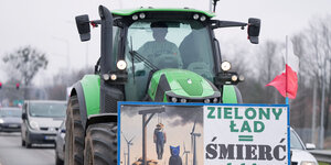 Ein Bauer in grünem Traktor. Davor ein Spruch auf polnisch "zielony ład = Śmierć" und ein Bild von einem Galgen
