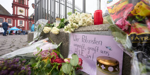 Blumen und ein Schild mit der Aufschrift: "Wer Polizisten angreift, greift uns alle an"