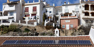 Spanische weiße Häuser stehen vor blauem Himmel, auf einem Ziegeldach sind Solarpanele angebracht