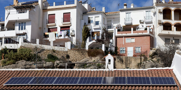 Spanische weiße Häuser stehen vor einem blauen Himmel, mit Sonnenkollektoren auf einem Ziegeldach montiert