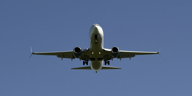 Fliegendes Passagierflugzeug von unten vor blauem Himmel