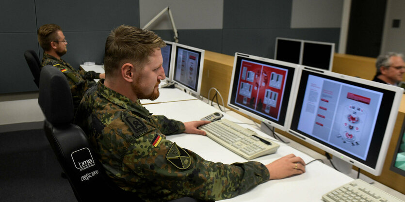 Uniformierte Soldaten an Coputerbildschirmen.