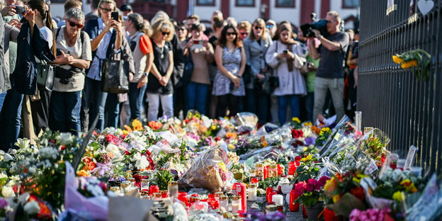 Menschen legen am Tatort auf dem Mannheimer Marktplatz Blumen für die Betroffenen nieder.