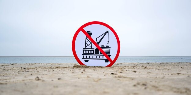 Ein Schild gegen die geplante Erdgasförderung steckt im Sand eines Strandes auf Borkum.