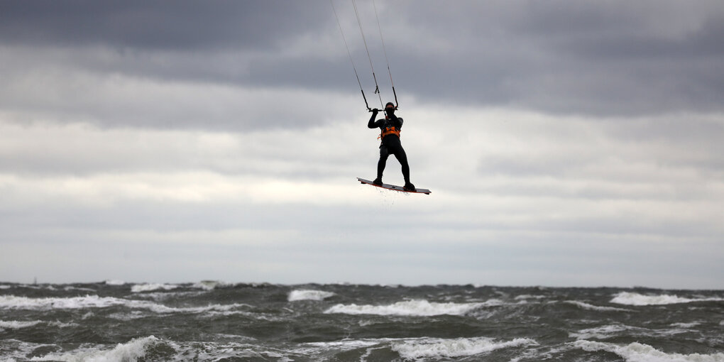 Kite Surfer erhebt sich über stürmischer Brandung