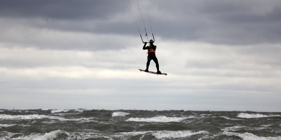 Kite Surfer erhebt sich über stürmischer Brandung