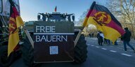 An einem großen Traktor ist ein Schild mit der Aufschrift "Freie Bauern" angebracht, links und rechts des Schildes sind große Flaggen der DDR angebracht
