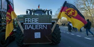 An einem großen Traktor ist ein Schild mit der Aufschrift "Freie Bauern" angebracht, links und rechts des Schildes sind große Flaggen der DDR angebracht