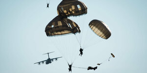 Soldaten hängen an olivgrünen Fallschirmen