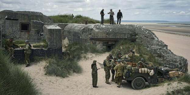 Menschen in historischen Uniformen auf einem Bunker am Strand