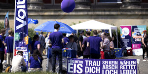 Wahlkampfstand der Partei Volt mit Luftballons die für mehr Eis werben, die Farbe der Plakate ist lila