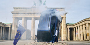 Protestaktion mit eine rauchenden Fahrzeug vor dem Brandenburger Tor.