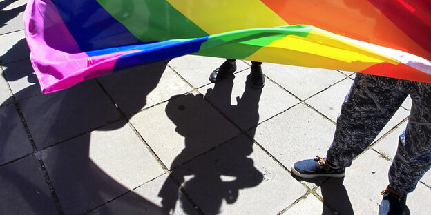 Menschen halten eine Regenbogenfahne.