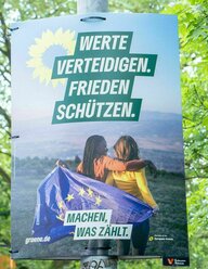 Wahlplakat der Grünen: Zwei junge Frauen stehen in der Landschaft, hinter ihnen die Europaflagge. Auf dem Plakat der Slogan: Werte verteidigen. Frieden schützen