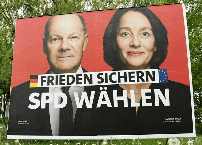 Wahlplakat der SPD: roter Hintergrund, die Porträts von Olaf Schol und Katharina Barley und der Slogan: Frieden sichern, SPD wählen