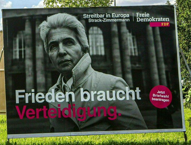 Wahlplakat der FDP: Porträt von Strack-Zimmermann mit hochgeschlagenem Mantelkragen vor dem Reichstag in Schwarz-weiss und dem Slogan: Frieden braucht Verteidigung