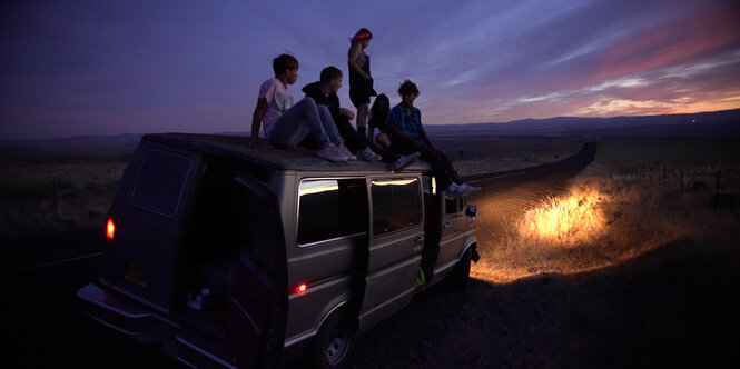 Jugendliche auf einem Camper in der weiten, amerikanischen Landschaft