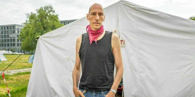 Wolfgang Metzeler-Kick steht vor einem Zelt im Protestcamp