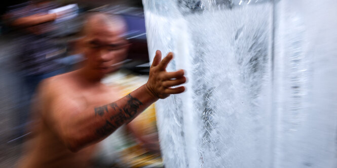 Ein Arbeiter in Thailand trägt einen großen Eisblock