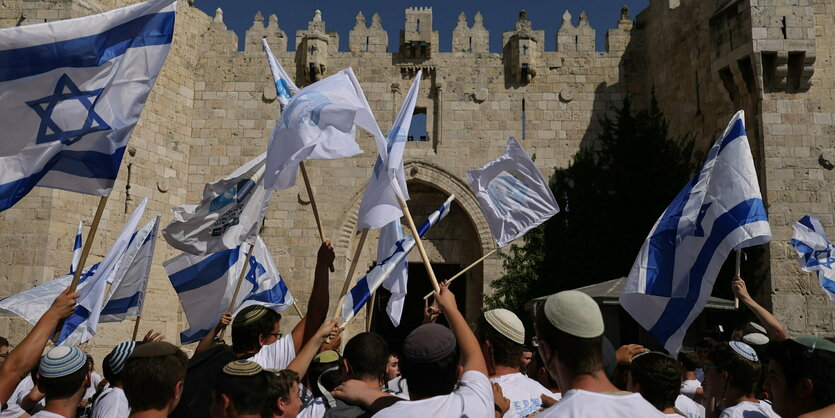 Menschen schwenken Israel-Flaggen vor dem Damaskustur in Jerusalem.