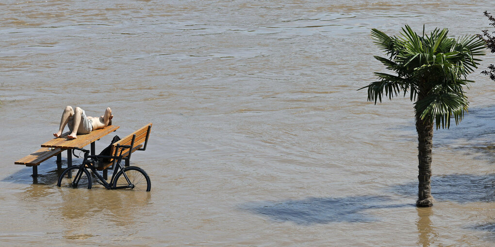 Eine Person auf einer Bank im Hochwasser.