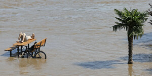 Eine Person auf einer Bank im Hochwasser.