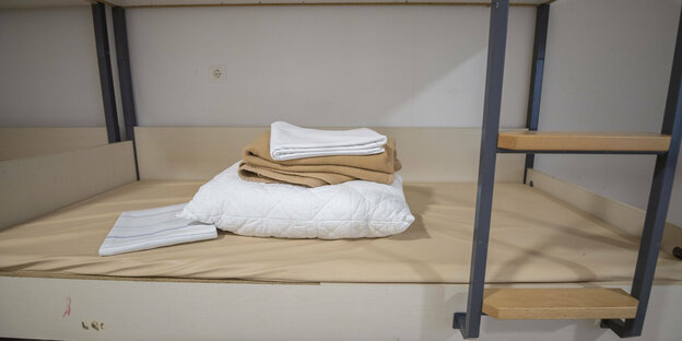 Decken, Kissen und Handtuch auf einem Bett in einer Notunterkunft