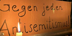 Eine brennende Kerze steht vor einem Schild mit der Aufschrift «Gegen jeden Antisemitismus» bei einer Mahnwache gegen Antisemitismus nach dem versuchten Brandanschlag auf die Synagoge in der Berliner Brunnenstraße.