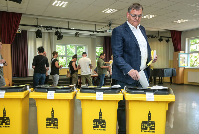 Eine Person bei der Stimmabgabe an einer Wahlurne.