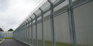 Eine mit Stacheldraht umzäunte Gefängnismauer