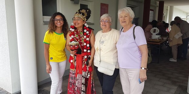 Kamila Costa im brasilianischen Trikot und Mira Rochyadi-Reetz in einem traditionellen indonesischen Gewand mit zwei Seniorinnen in Ilmenau