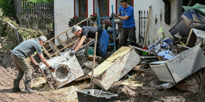 Mehrere Personen vor einem überschwemmten Haus.