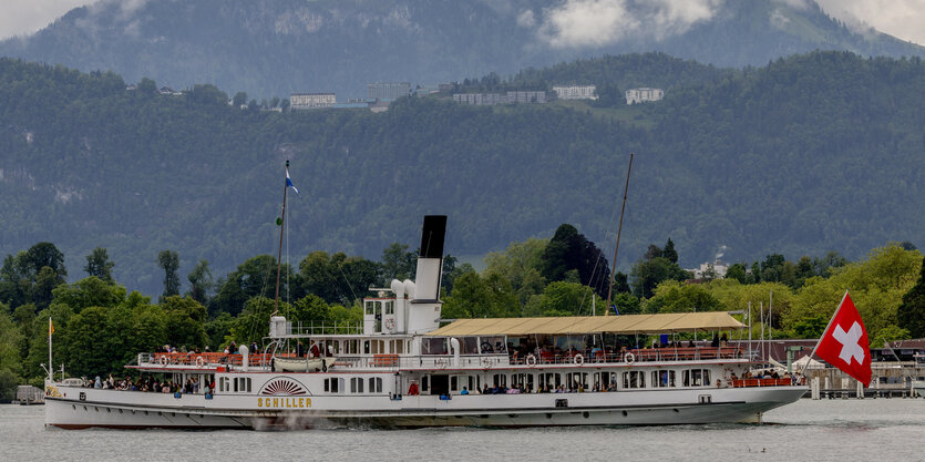 Ein Schiff mit Schweizer Flagge fährt über einen See