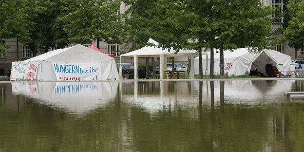 Ein Protestcamp in Berlin hinter einer Wasserfläche