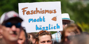 Ein Schild „Faschismus macht hässlich“ hält ein Teilnehmer der Kundgebung «Hand in Hand für Demokratie und Menschenrechte» gegen Rechtsextremismus in Leipzig