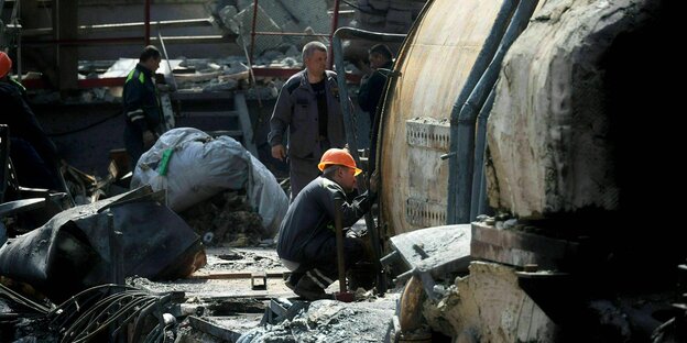 Arbeiter mit Helmen arbeiten an beschädigten Maschinen