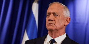 Benny Gantz steht vor einem blauen Hintergrund und schaut grimmig