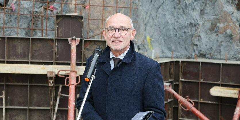 Ein Mann im schwarzen Mantel steht auf einer Baustelle