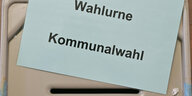 Ein Zettel mit der Aufschrift «Wahlurne Kommunalwahl» liegt auf einer Wahlurne in einem Wahllokal.