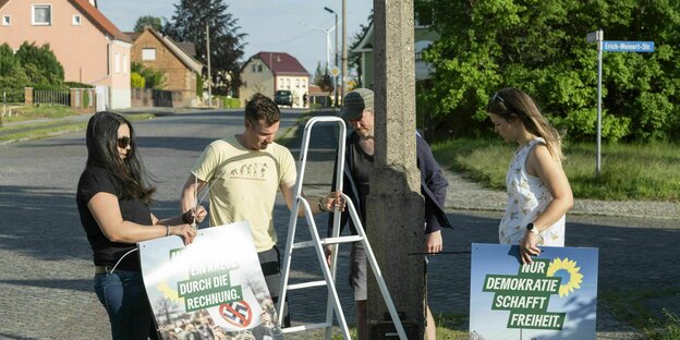 Stefan Neuberger, Ines Neuberger (helles Shirt), Frank (Mütze) und Carolin Poensgen hängen Wahlplakate für die Grünen in Lauchhammer