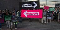 Demonstranten halten zwei Banner in die Luft: "Far Right" und "Freedom", mit Pfeilen in entgegengesetzter Richtung.